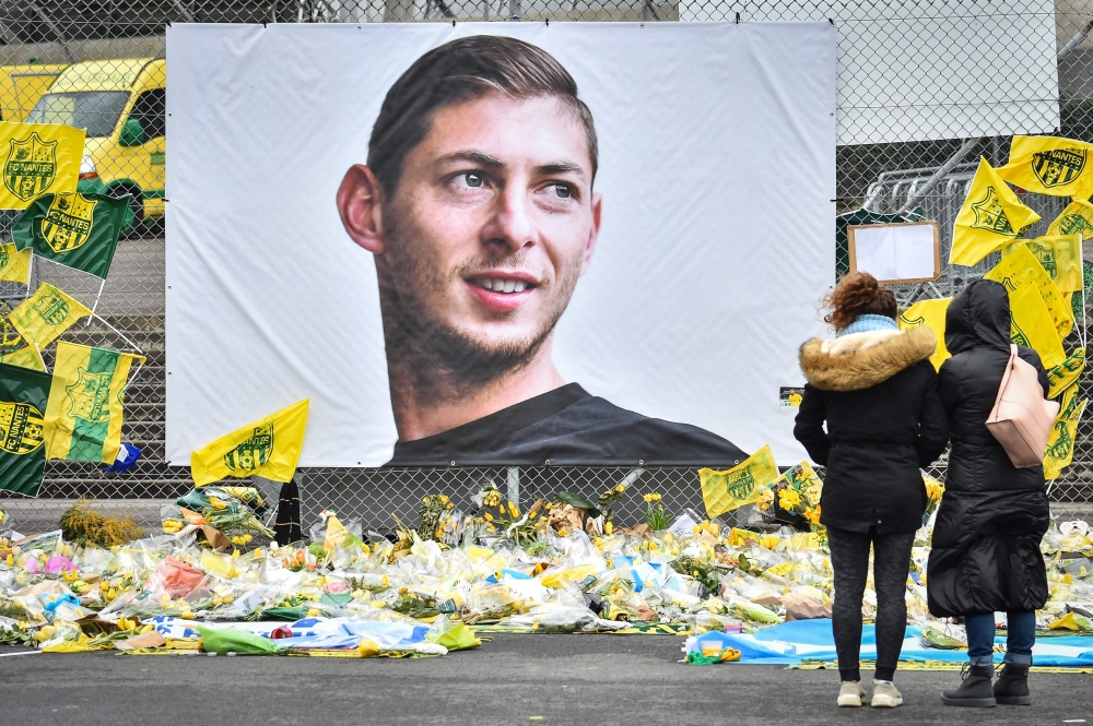 FILE PHOTO: People look at yellow flowers displayed in front of the portrait of Argentinian forward Emiliano Sala at the Beauvoir stadium in Nantes, on February 8, 2019.  AFP / LOIC VENANCE