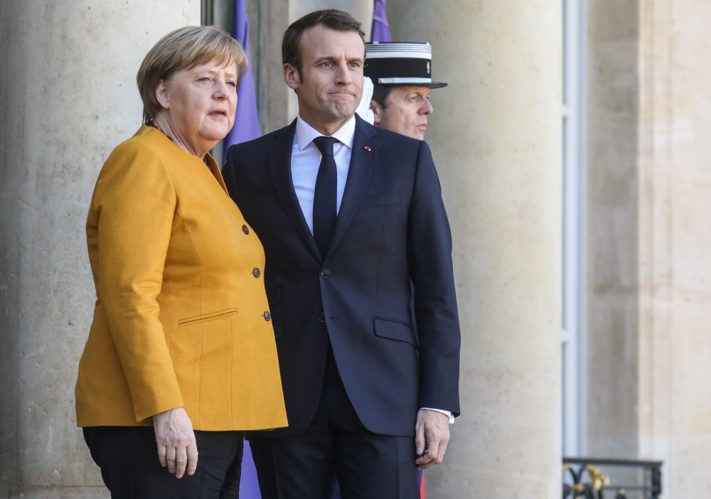 French President Emmanuel Macron (R) poses next to German Chancellor Angela Merkel as she arrives for a meeting at the Elysee Palace on Febuary 27, 2019, in Paris. / AFP / Ludovic MARIN