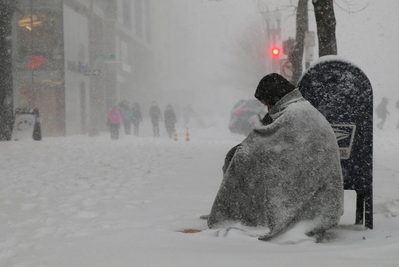 A homeless man asks for money outside a donut shop during white-out, blizzard-like conditions in a winter nor'easter snow storm in Boston, Massachusetts. February 9, 2017. Reuters/Brian Snyder
 