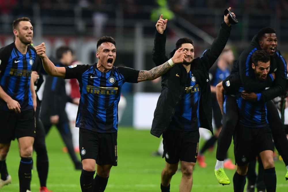 Inter Milan's Argentine forward Lautaro Martinez (L), Inter Milan's Italian midfielder Matteo Politano (C-R) and teammates celebrate winning the Italian Serie A football match AC Milan vs Inter Milan at the San Siro stadium in Milan. / AFP / Miguel MEDINA
