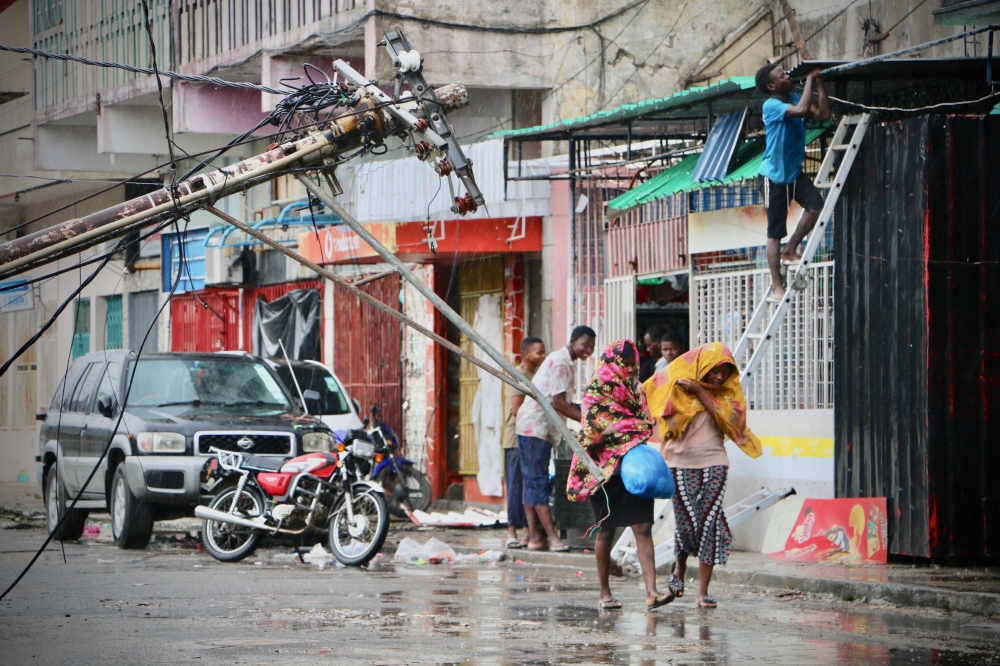 Residents are seen protecting themselves by the rain in the aftermath of the passage of the cyclone Idai in Beira, Mozambique, on March 17, 2019.   AFP / ADRIEN BARBIER
