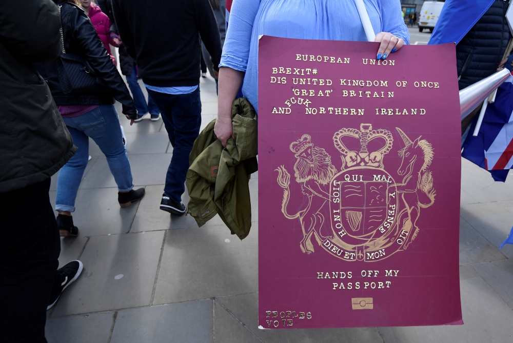 A mock-up of a British Passport is held by an anti-Brexit protester outside of the Houses of Parliament, in London, Britain, March 18, 2019. Reuters/Toby Melville