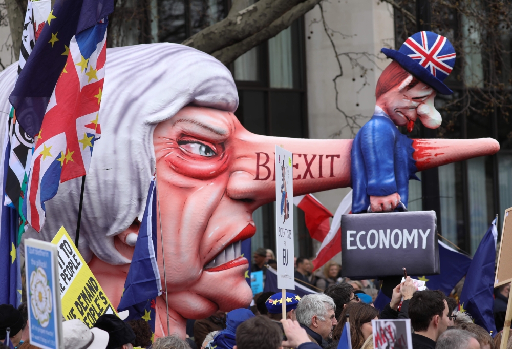 A puppet head of Britain's Prime Minister Theresa May spearing a representation of the British Economy is taken on a march and rally organised by the pro-European People's Vote campaign for a second EU referendum in central London on March 23, 2019. AFP /