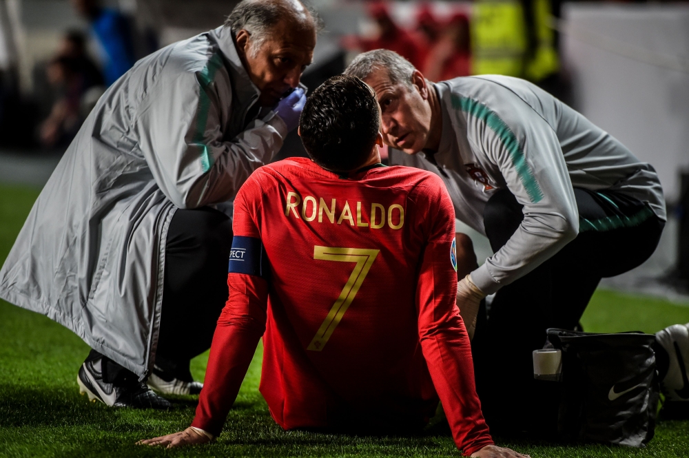 Doctors check on Portugal's forward Cristiano Ronaldo during the Euro 2020 qualifying group B football match between Portugal and Serbia at the Luz stadium in Lisbon on March 25, 2019. / AFP / PATRICIA DE MELO MOREIRA