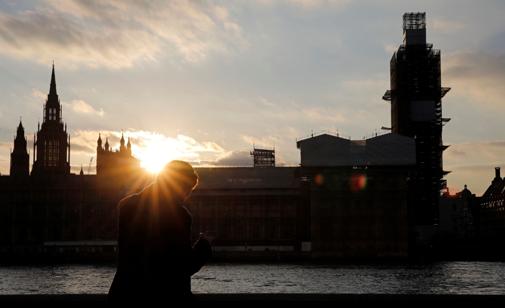 A man stands on the banks of River Thames, across from the Houses of Parliament in Westminster, in central London on March 27, 2019.  AFP / Tolga Akmen 