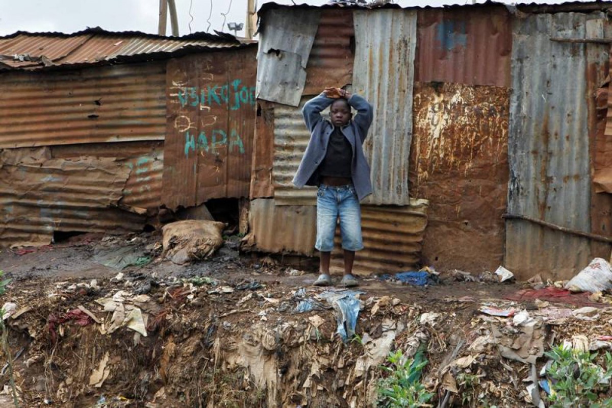 A child stands behind pit latrines made of rusted iron sheets in Kibera slum within Nairobi, Kenya February 24, 2019. Reuters/Njeri Mwangi