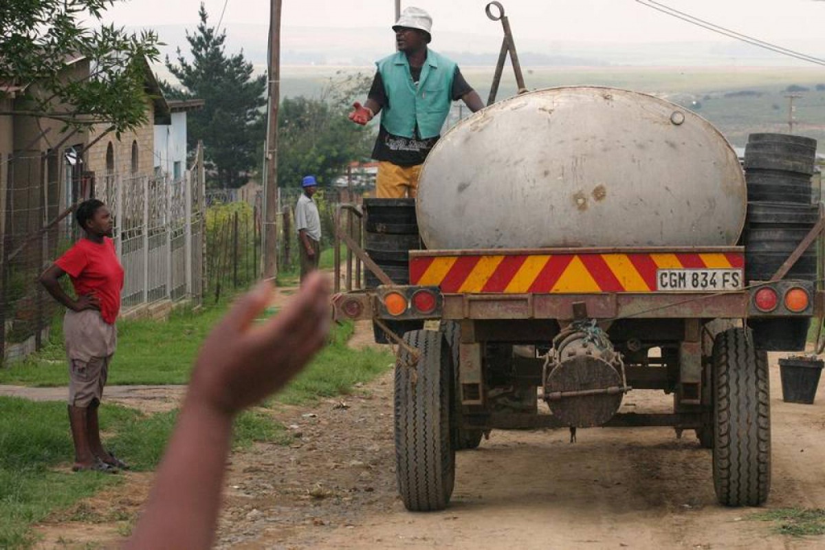 Residents greet workers collecting buckets of raw sewage from homes in the Ezenzeleni township, about 200 km (124 miles) south of Johannesburg, February 8, 2006. Reuters/Siphiwe Sibeko