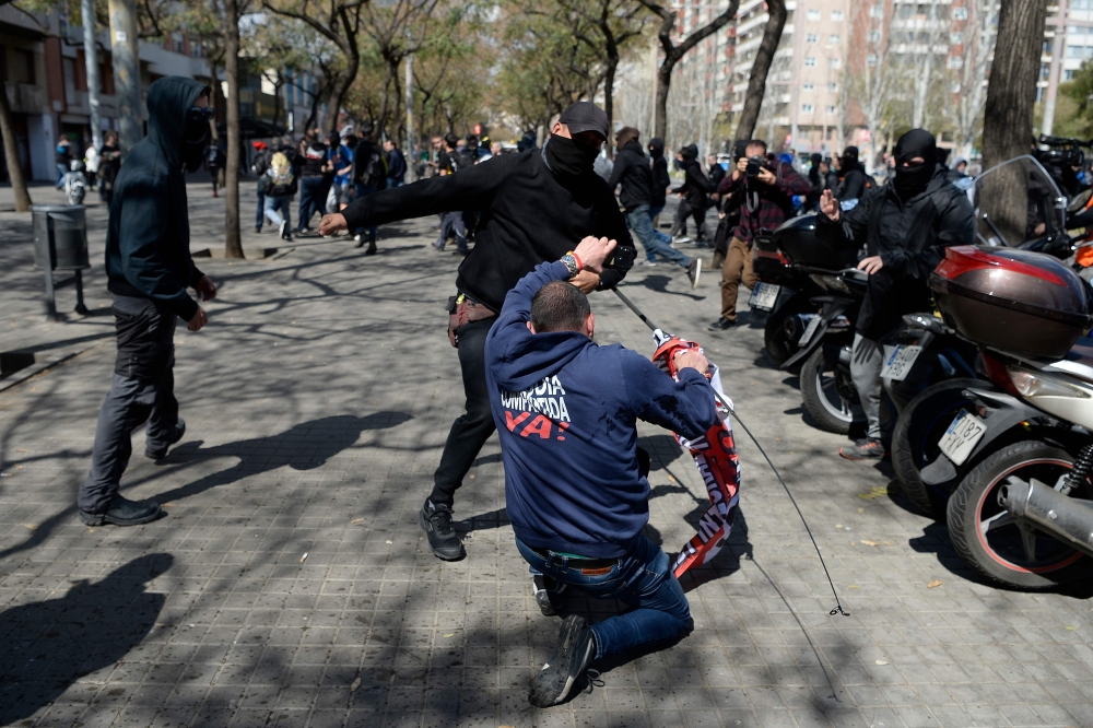 A Catalan pro-independence protester (back) scuffles with a supporter of Spanish far-right party Vox after pro-independence supporters staged a counter demonstration during a protest by Vox against the Catalan independence push in Barcelona on March 30, 2