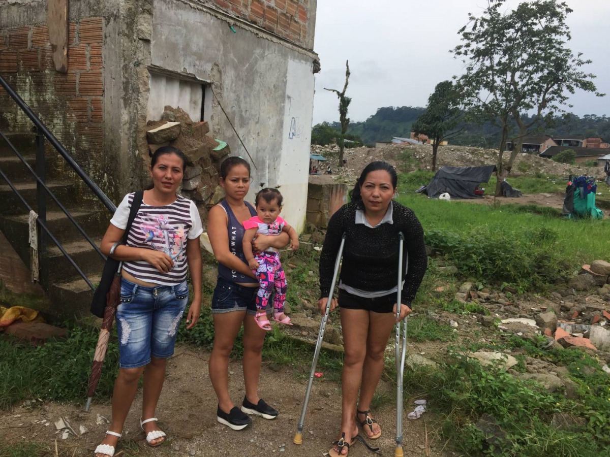 Landslide survivor Eugenia Torres (left) and her friends stand behind a home in a flood prone area in Mocoa,Colombia. March 28, 2019. Thomson Reuters Foundation /Anastasia Moloney