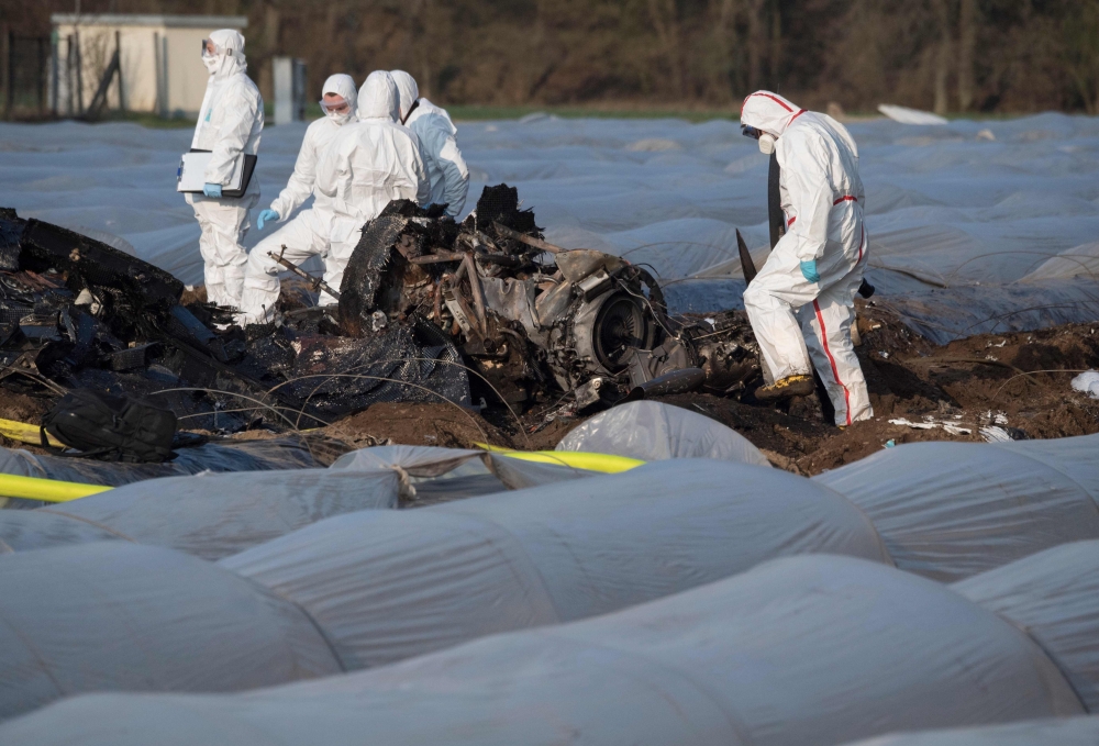 Forensic experts and police inspect the burnt out remains of a small plane lie on an asparagus field after it crashed the day before in Erzhausen near Darmstadt, Germany on April 1, 2019.  AFP / Boris Roessler
