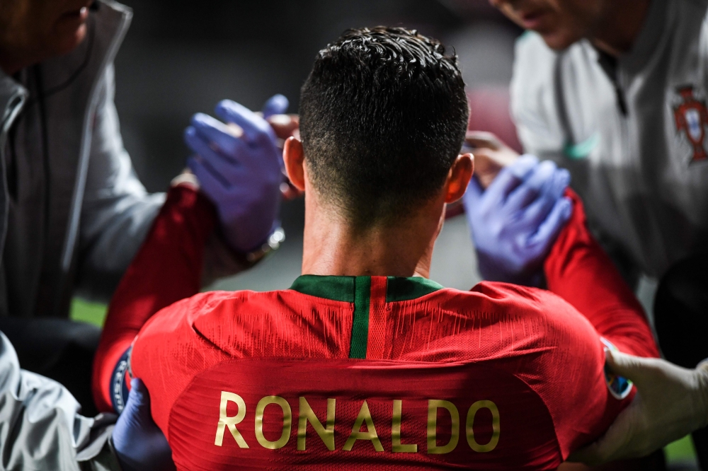 FILE PHOTO: Portugal's forward Cristiano Ronaldo is attended by doctors during the Euro 2020 qualifying group B football match between Portugal and Serbia at the Luz stadium in Lisbon on March 25, 2019. / AFP / PATRICIA DE MELO MOREIRA