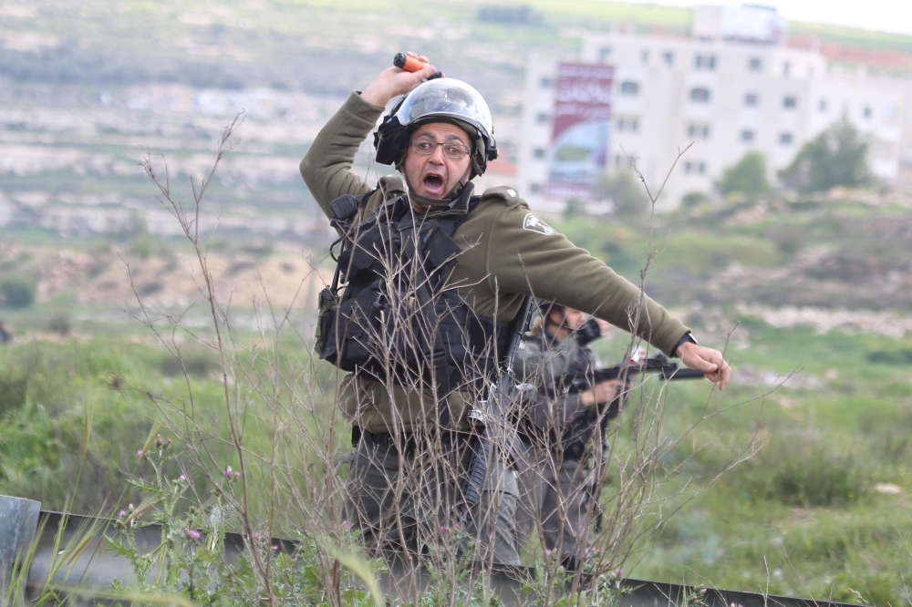 An israeli soldier throws tear gas at Birzeit University students during a protest after Israeli forces take 3 students into custody, near Beit Il Israeli military check point in Ramallah, West Bank on March 27, 2019. (?ssam Rimawi/Anadolu Agency)
 