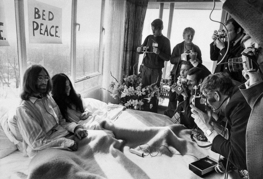 Beatles member John Lennon (L) and his wife Yoko Ono receive journalists in the bedroom of the Hilton hotel in Amsterdam, during their honeymoon in Europe on March 25, 1969. AFP / ANP 