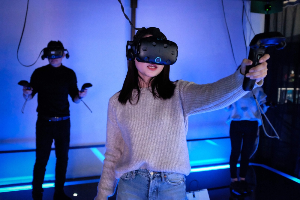 In this photo taken on February 13, 2019, a woman plays a video game using a virtual-reality headset at an arcade in Shanghai. AFP/Matthew Knight 