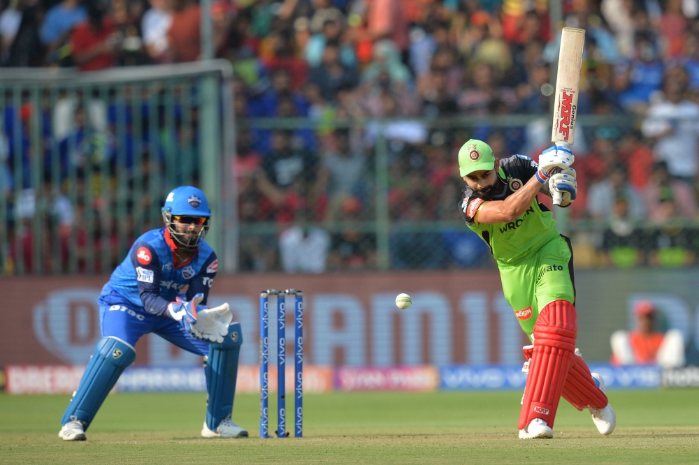 Royal Challengers Bangalore batsman and captain Virat Kohli (R) plays a shot while Delhi Capitals wicketkeeper Rishab Pant looks on during the 2019 Indian Premier League (IPL) Twenty20 cricket match between Royal Challengers Bangalore and Delhi Capitals a