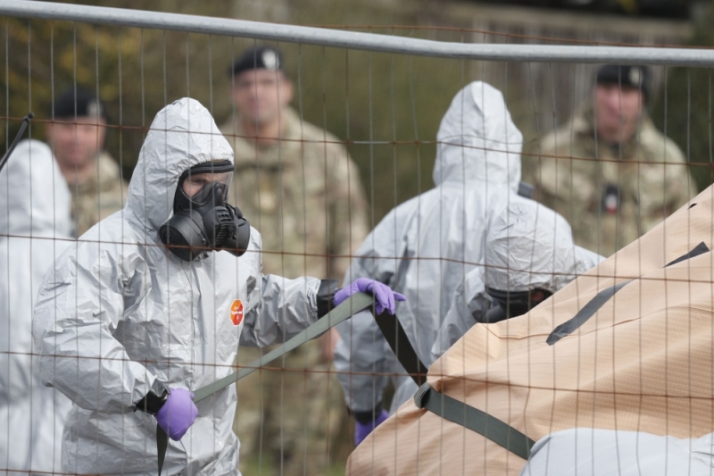 British military personnel wearing protective coveralls work to remove a vehicle connected to the March 4 nerve agent attack in Salisbury from a residential street in Gillingham on March 14, 2018. AFP/Adrian Dennis