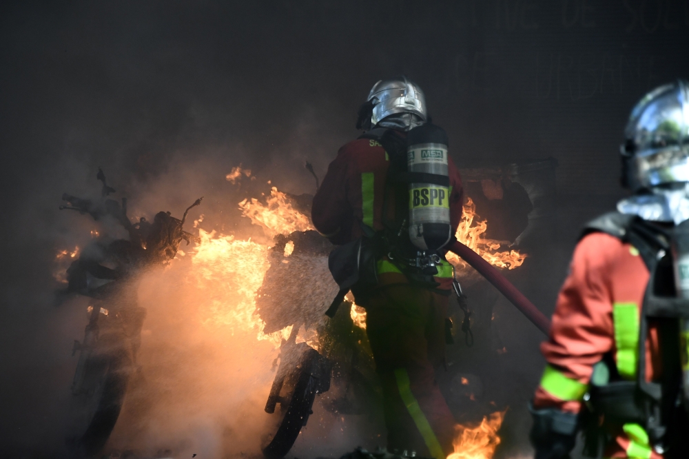 Firefighters extinguish burning scooters and motorbikes set on fire during an anti-government demonstration called by the 