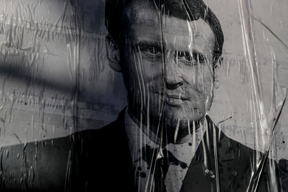 A poster displayed and stained by Climate change activists depicting French President Emmanuel Macron, during an environmental protest called by the NGO Extinction Rebellion, in La Defense, near Paris. / AFP / Thomas SAMSON