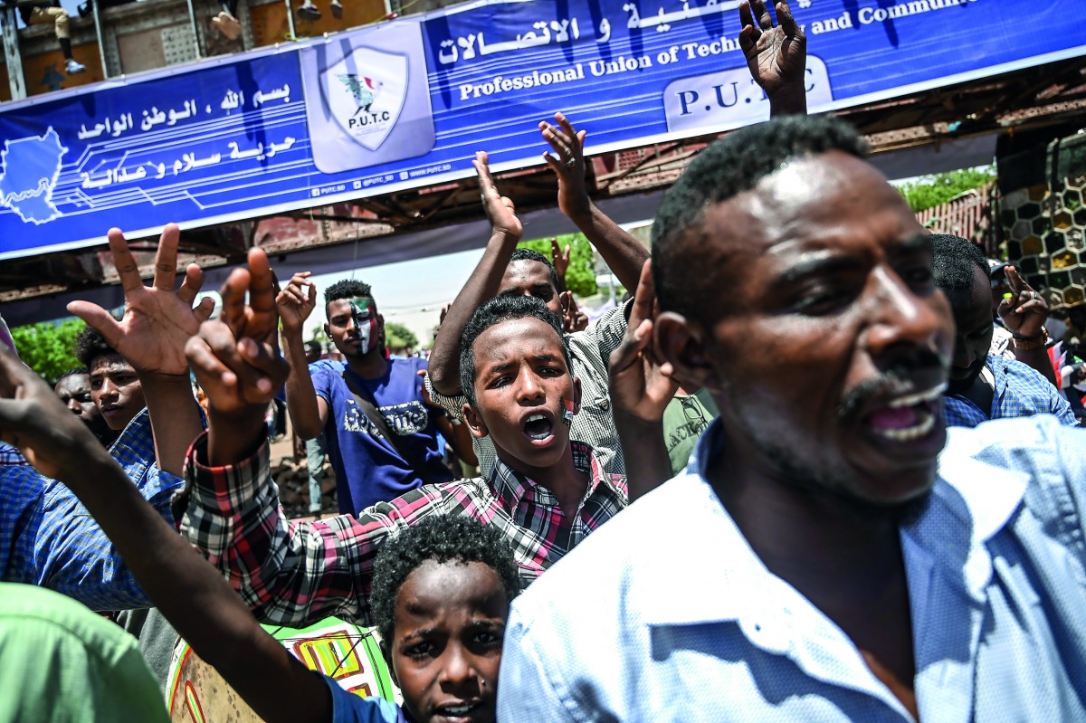 Sudanese protesters flash the V for victory signs as they shout slogans during a protest near the army hearquarters in the capital Khartoum on April 21, 2019. AFP / Ozan Kose 