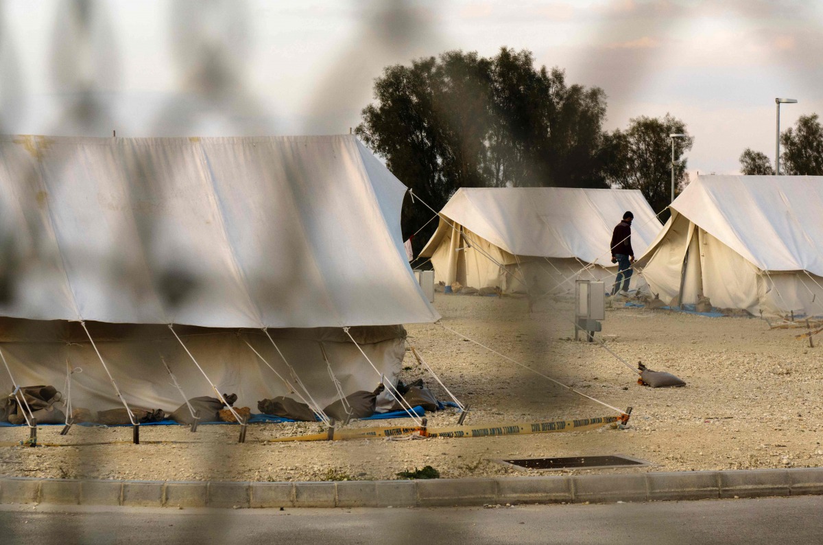 A Syrian refugee walking in between tents at a reception centre in Kokkinotrimithia on the outskirts of the Cypriot capital Nicosia on March 07, 2017. AFP/Iakovos Hatzistavrou