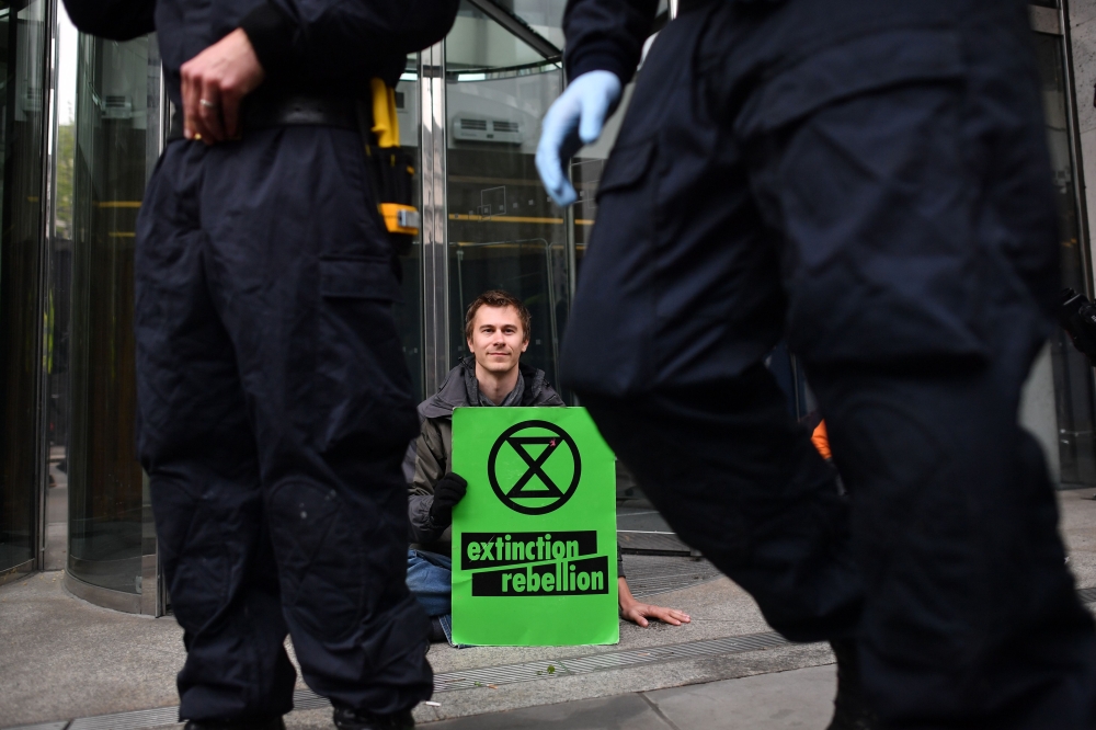 Climate change activists who glued themselves to the pavement block the entrance to the London stock exchange during protests by the Extinction Rebellion group in London on April 25, 2019. / AFP / Ben STANSALL