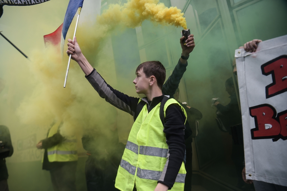 A protester holds up the French flag during a rally in the French capital Paris, on the 24th consecutive Saturday of demonstrations called by the 'Yellow Vest' (gilets jaunes) anti-government movement and the Trade Unions on April 27, 2019.   AFP / Lucas 