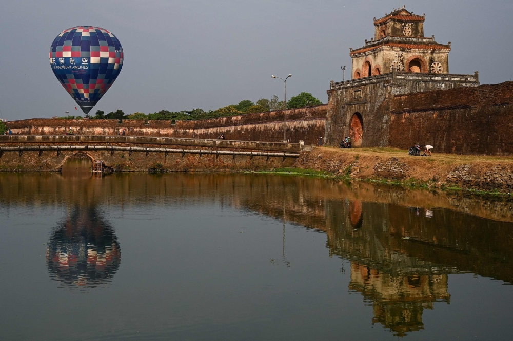 A hot air balloon flies over the former capital's stone citadel during a hot air balloon festival in the central Vietnamese city of Hue on April 28, 2019. AFP / Manan Vatsyayana 