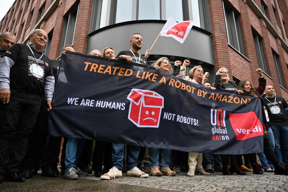 Representatives of Amazon workers hold a banner reading 
