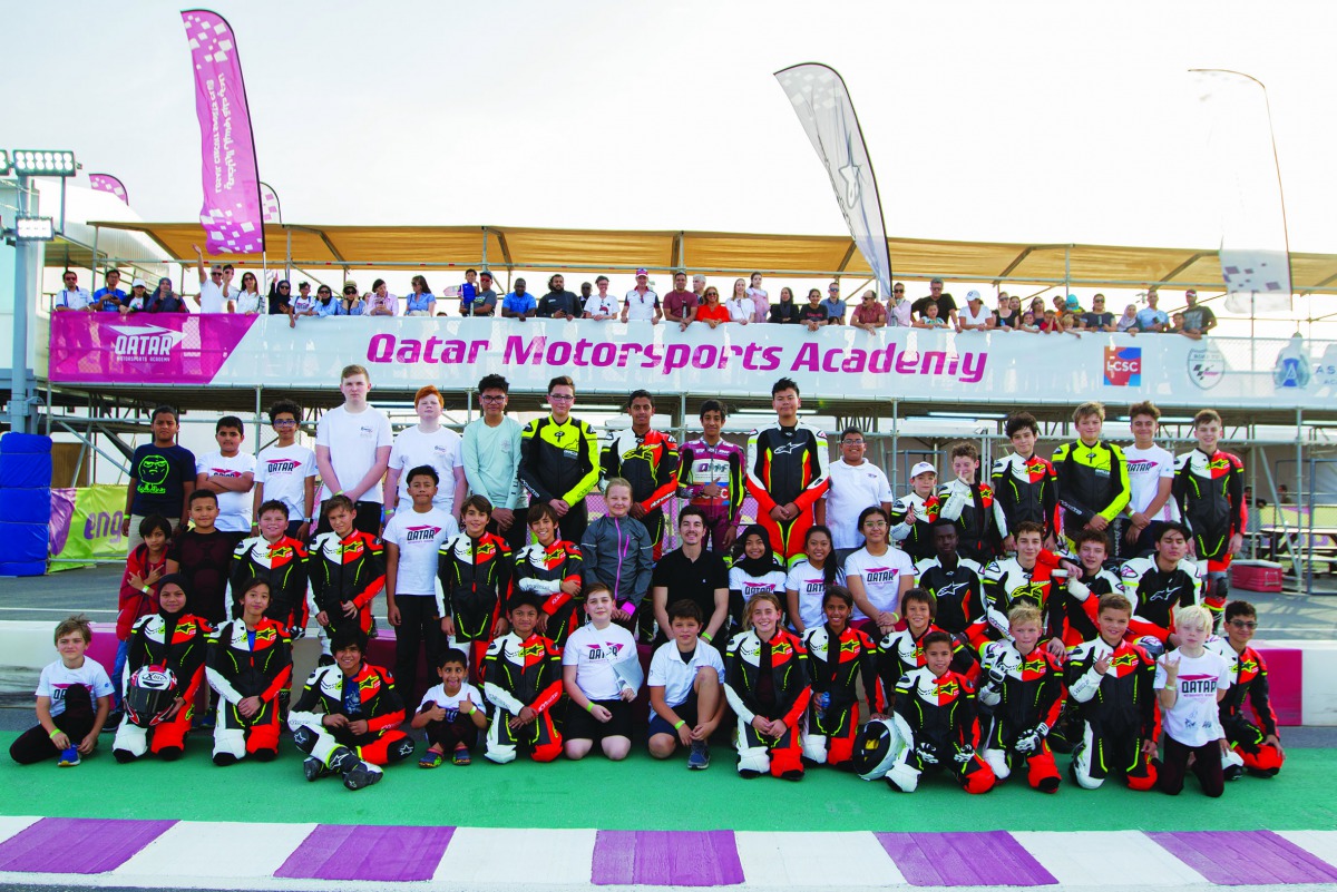 Vinales (third row centre), poses for a picture with children, who are part of the Qatar Motorsports Academy, at the Losail International Circuit.