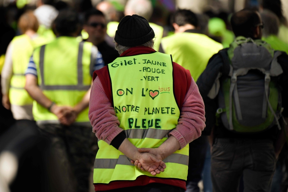 A protester wears a yellow vest on which is written 'yellow, red or green vest, we all love our blue planet', during an anti-government demonstration called by the 'Yellow Vest' (Gilets Jaunes) on April 27, 2019 in Marseille.  AFP / GERARD JULIEN