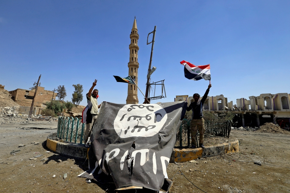 Shi'ite Popular Mobilization Forces (PMF) members hold an Islamic State flag, which they pulled down, during the war between Iraqi army and Shi'ite Popular Mobilization Forces (PMF) against the Islamic State militants in Tal Afar, Iraq August 27, 2017. Re