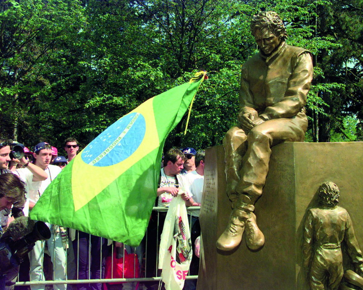 This April 25, 1997 file photo shows fans carrying a Brazilian flag gather to see the unveiling of a statue of former Brazilian Formula One driver Ayrton Senna, at the spot on the Imola racetrack where Senna was killed on May 1, 1994 during the San Marino