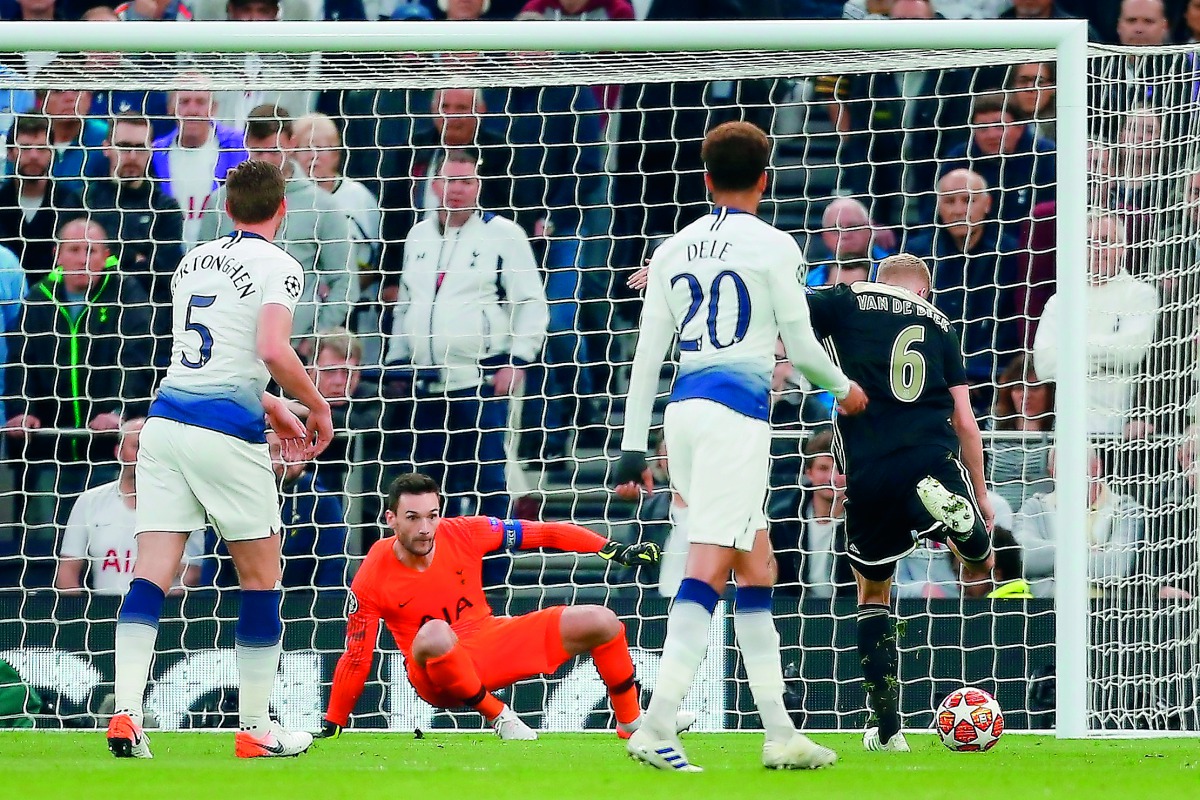 Ajax's Dutch midfielder Donny Van de Beek (R) shoots past Tottenham Hotspur's French goalkeeper Hugo Lloris (2L) to score the opening goal during the UEFA Champions League semi-final first leg football match between Tottenham Hotspur and Ajax at the Totte