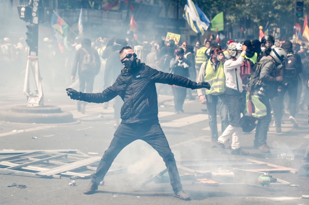 A masked protester dressed in black throws a projectile to riot police officers, prior to the start of May Day demonstrations, in Paris on May 1, 2019.  AFP / Zakaria ABDELKAFI