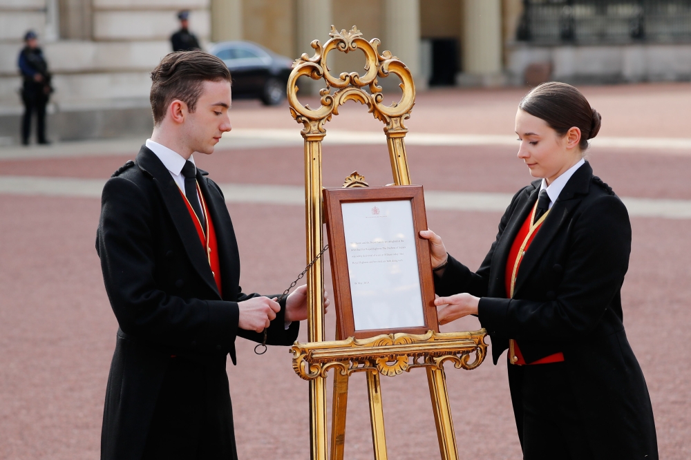Members of staff set up an official notice on an easel at the gates of Buckingham Palace in London on May 6, 2019 announcing the birth of a son to Britain's Prince Harry, Duke of Sussex and Meghan, Duchess of Sussex. (AFP / Tolga AKMEN)