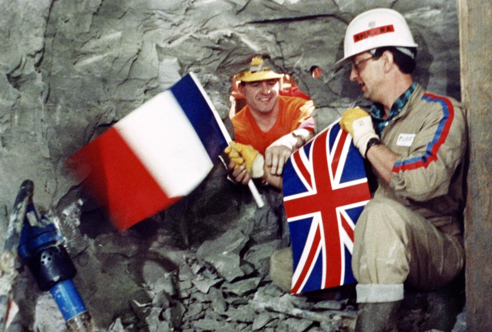 Tunnel workers Philippe Cozette from France (R) and Graham Fagg from England shake hands while holding national flags, during the historic breakthrough in the Channel Tunnel on December 1, 1990. AFP