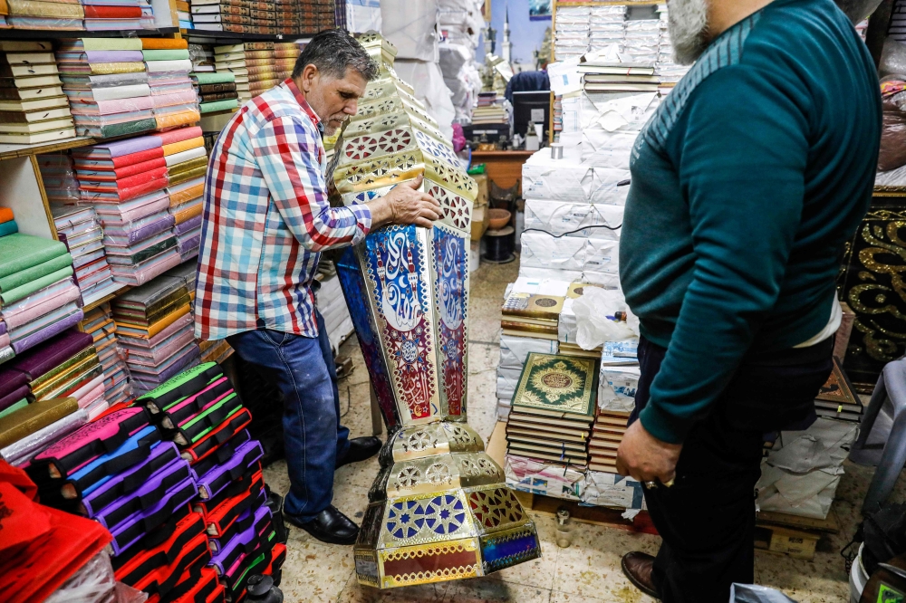 Palestinian craftsman Issam Zughair (L) moves a large Ramadan lantern in his shop in the old city of Jerusalem on May 2, 2019. AFP / AHMAD GHARABLI
