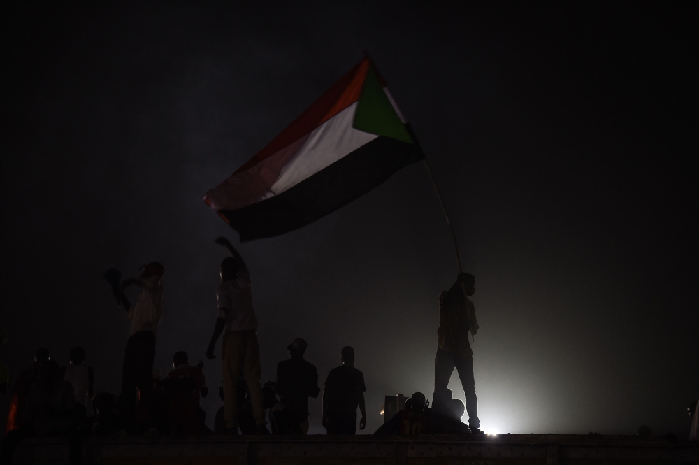 Sudanese protesters wave national flags at the sit-in outside the army headquarters in Khartoum on May 9, 2019. / AFP / Mohamed el-Shahed