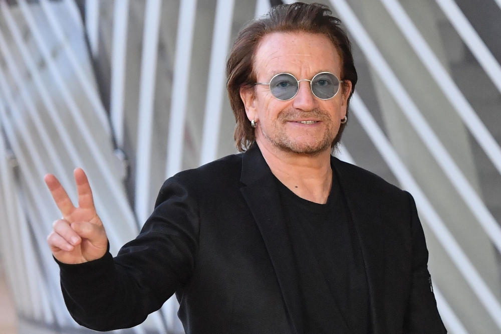 U2 singer Bono flashes the Victory sign upon his arrival at the European Council in Brussels on October 10, 2018. AFP / Emmanuel Dunand