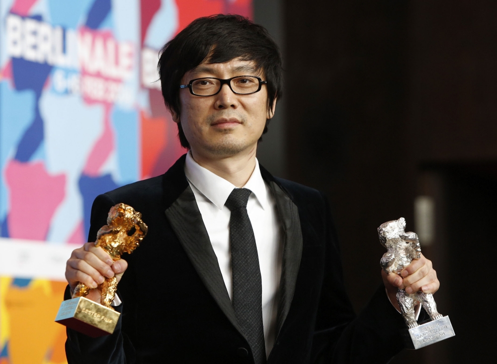 Chinese director Diao Yinan poses with the Golden Bear for Best Film and the Silver Bear for Best Actor trophies during a press conference following the awarding ceremony of the 64th Berlinale Film Festival on February 15, 2014.  AFP / David Gannon 