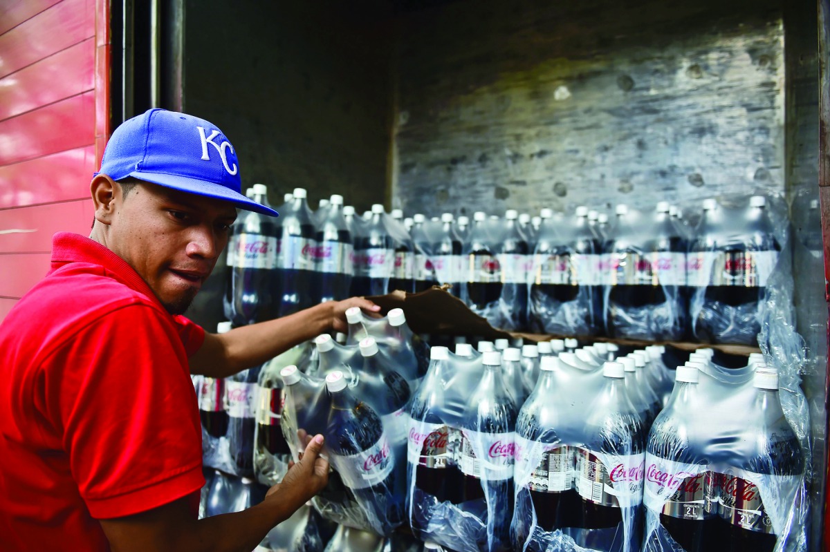 A man unloads bottles of Coca Cola from a truck in Caracas on May 27, 2016. AFP/Ronaldo Schemidt