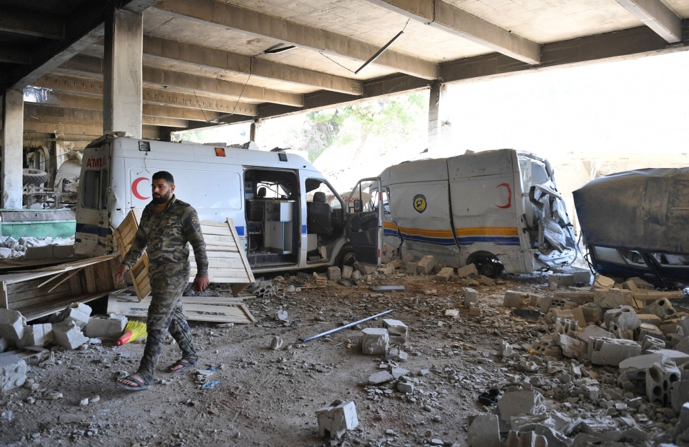 A Syrian government soldier walks past destroyed ambulances and vehicles of the Syrian Civil Defence, also known as 