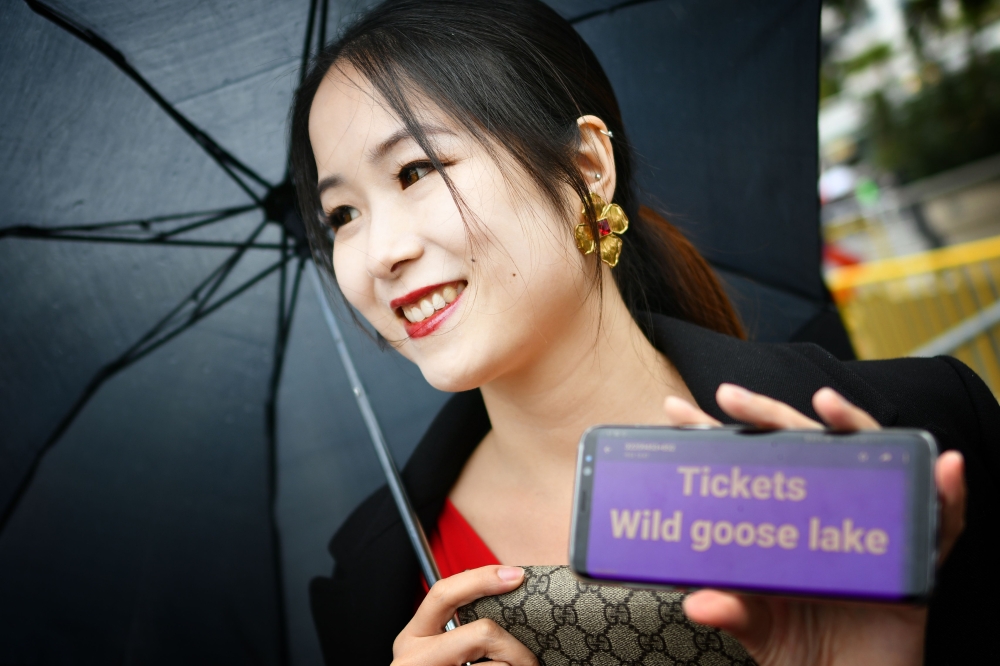 A festival goer holds up her mobile phone asking for invitations for the screening of the film 