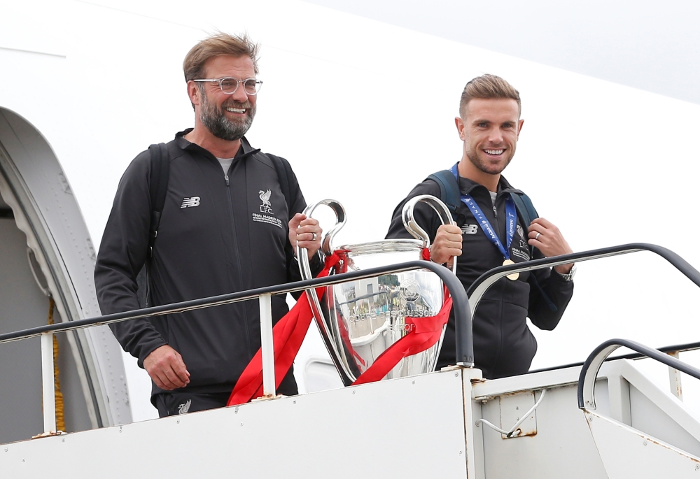 Liverpool's Jordan Henderson and manager Juergen Klopp emerge from an aeroplane with the trophy as they arrive back in Liverpool after winning the Champions League Final. Reuters/Craig Brough