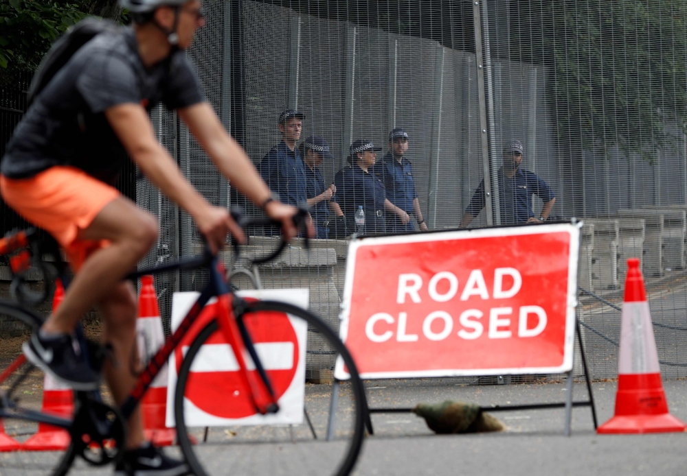 British police officers stand on duty behind the security fences in Regents Park, erected around The Residence of the US Ambassador to the UK, Winfield House, where US President Donald Trump is expected to stay during his visit this coming week, in centra