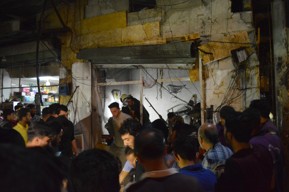 People gather around the wreckage of shops after a terror attack with a bomb-laden vehicle carried out in Azez district of Aleppo, Syria on June 02, 2019. According to reports at least 14 civilians were killed after the attack. (Saher el Hacci/Anadolu Age