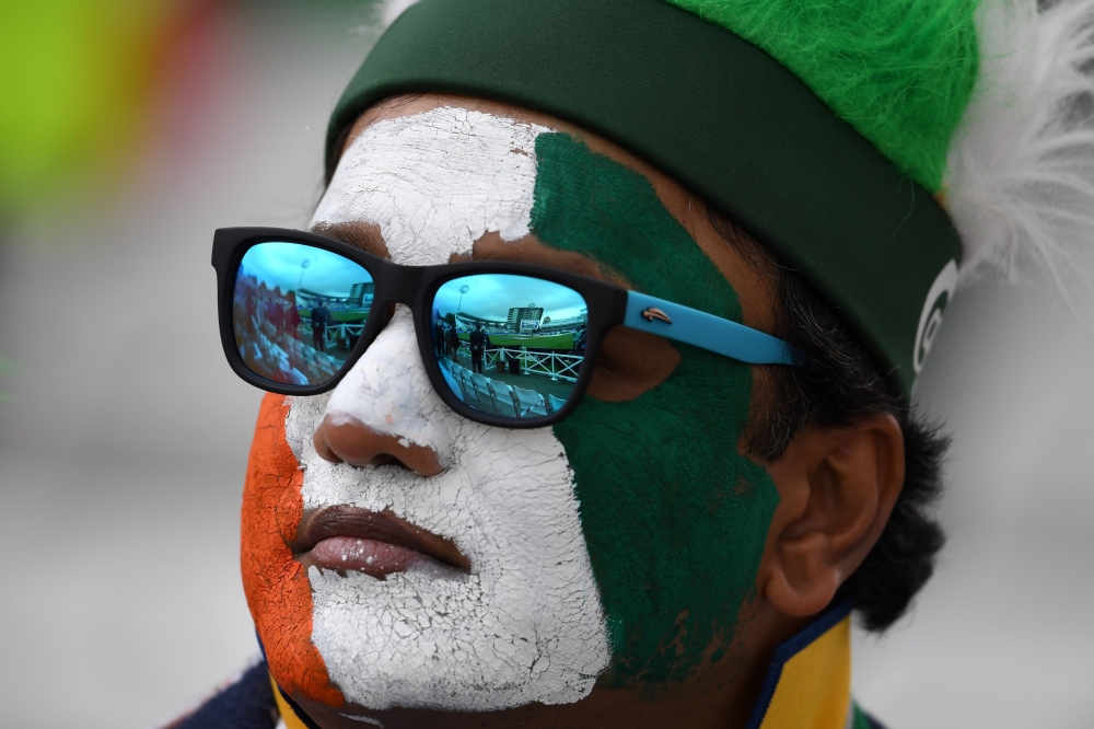 An Indian supporter poses with his face painted in the national colours as play is delayed in the 2019 Cricket World Cup group stage match between India and New Zealand at Trent Bridge in Nottingham, central England, on June 13, 2019.  AFP / Dibyangshu Sa