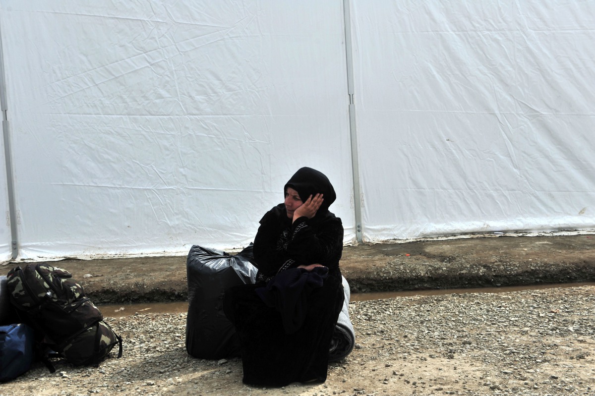 A migrant woman waits at a makeshift camp at the Greek-Macedonian border near the Greek village of Idomeni on March 26, 2016. AFP/Sakis Mitrolidis