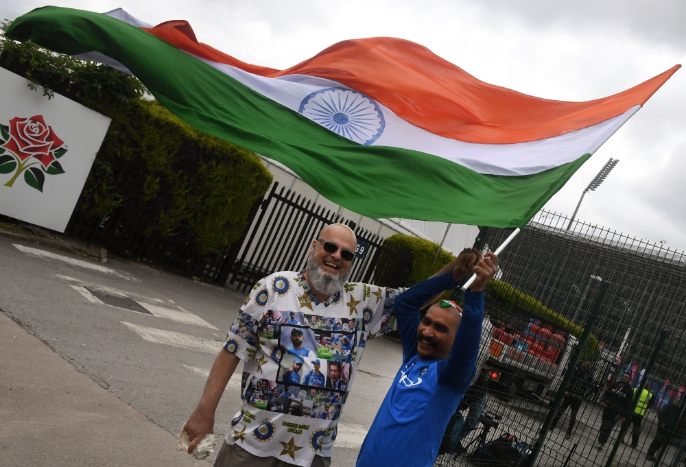 Indian cricket fan Sudir Gautam (R) and Pakistani cricket fan Mohammad Bashir wave the Indian tricolour at Old Trafford Cricket Stadium in Manchester on June 15, 2019, ahead of the 2019 World Cup match between India and Pakistan. AFP / Dibyangshu Sarkar 