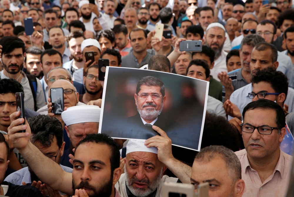 A man holds a picture of the former Egyptian president Mohamed Mursi during a symbolic funeral prayer at the courtyard of Fatih Mosque in Istanbul, Turkey, June 18, 2019. Reuters/Murad Sezer 